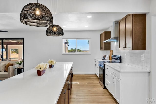 kitchen with light countertops, wall chimney range hood, white cabinetry, and stainless steel electric stove