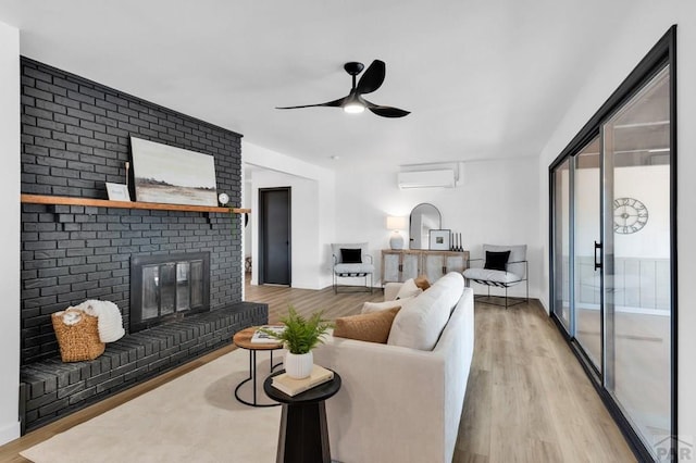 living area featuring ceiling fan, a wall mounted AC, a brick fireplace, and light wood-style floors