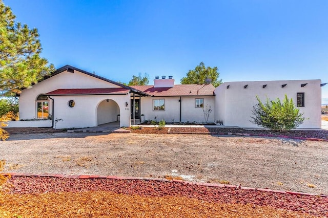 view of front facade featuring a chimney and stucco siding