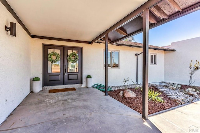 view of exterior entry with stucco siding, a patio area, and french doors