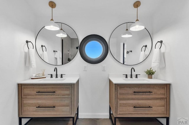 bathroom featuring baseboards, two vanities, a sink, and tile patterned floors