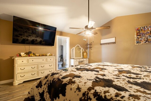 bedroom featuring baseboards, ceiling fan, ensuite bath, vaulted ceiling, and light wood-type flooring