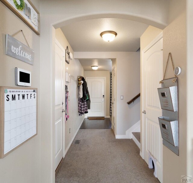 hallway with visible vents, baseboards, stairway, carpet, and mail area