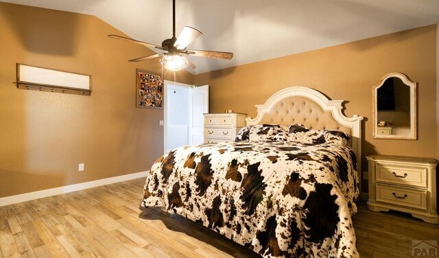 bedroom with a ceiling fan, lofted ceiling, light wood finished floors, and baseboards