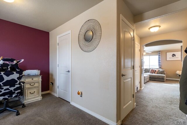 carpeted office with baseboards and arched walkways