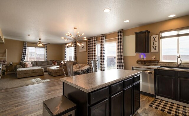 kitchen featuring a center island, stainless steel dishwasher, open floor plan, a sink, and wood finished floors