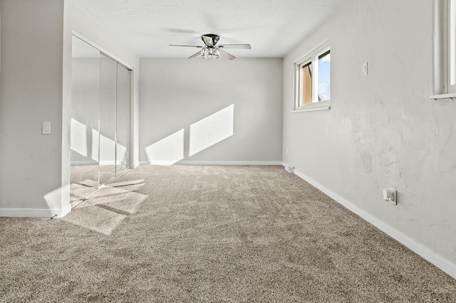 carpeted spare room featuring baseboards and a ceiling fan