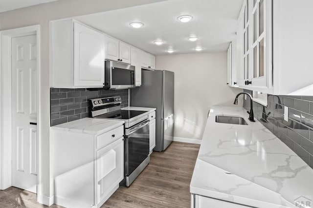 kitchen featuring dark wood-type flooring, a sink, white cabinets, appliances with stainless steel finishes, and light stone countertops