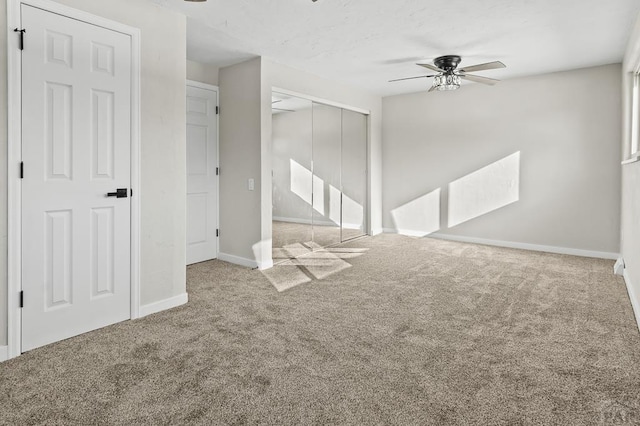 unfurnished living room with carpet flooring, ceiling fan, and baseboards