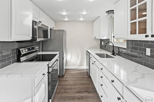 kitchen with baseboards, white cabinets, dark wood-style floors, stainless steel appliances, and a sink