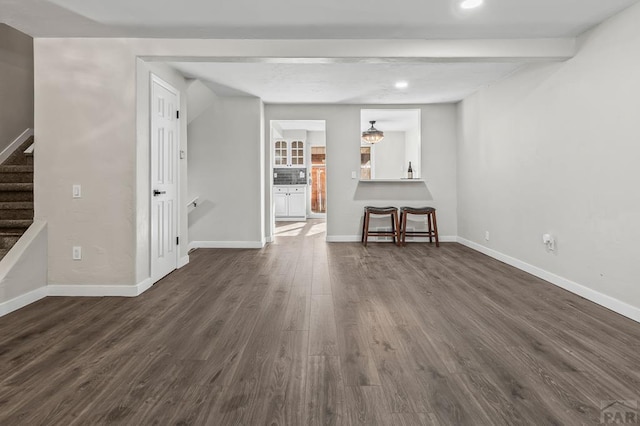 empty room with beam ceiling, recessed lighting, dark wood-type flooring, baseboards, and stairs