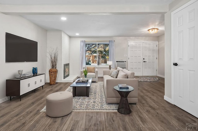 living area with a fireplace, baseboards, and wood finished floors