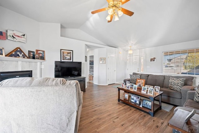 living room with a fireplace, a ceiling fan, vaulted ceiling, and wood finished floors