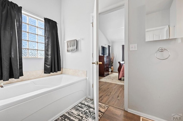 full bathroom with a garden tub, baseboards, connected bathroom, and wood finished floors