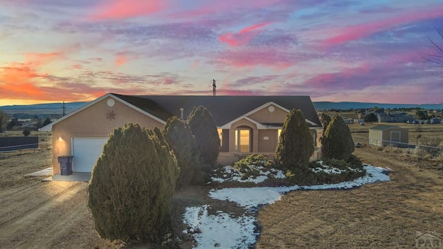 ranch-style home featuring a garage, an outbuilding, driveway, and stucco siding