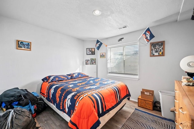 bedroom featuring dark wood-style floors, baseboards, and a textured ceiling