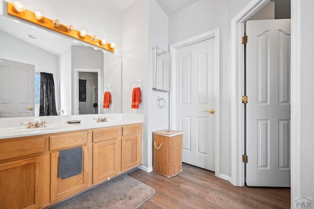 full bathroom featuring lofted ceiling, double vanity, wood finished floors, and a sink