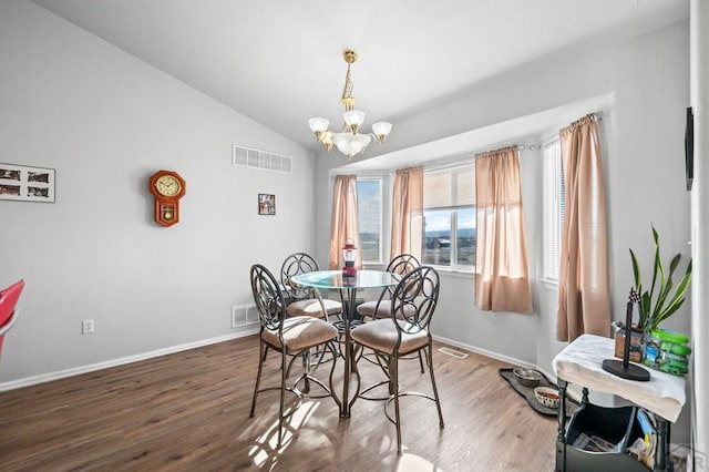 dining space with visible vents, vaulted ceiling, wood finished floors, and a chandelier