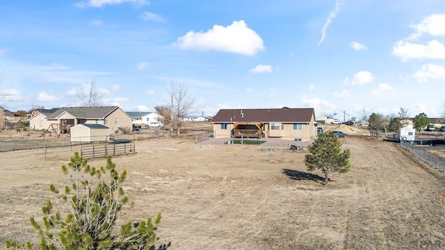 rear view of property with a residential view, an exterior structure, fence, and an outbuilding