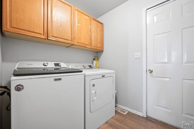 laundry room with washing machine and dryer, visible vents, baseboards, cabinet space, and dark wood-style floors