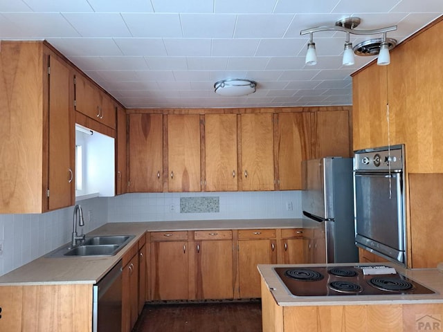 kitchen featuring brown cabinets, appliances with stainless steel finishes, a sink, and light countertops
