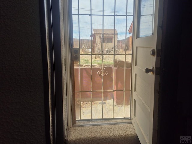 doorway to outside with a wealth of natural light, carpet, and a textured wall