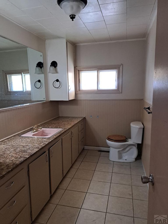 bathroom featuring wainscoting, plenty of natural light, toilet, and tile patterned floors