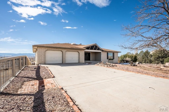 view of front of home with a garage, driveway, fence, and brick siding