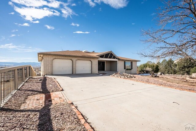 view of front of house with brick siding, driveway, an attached garage, and fence