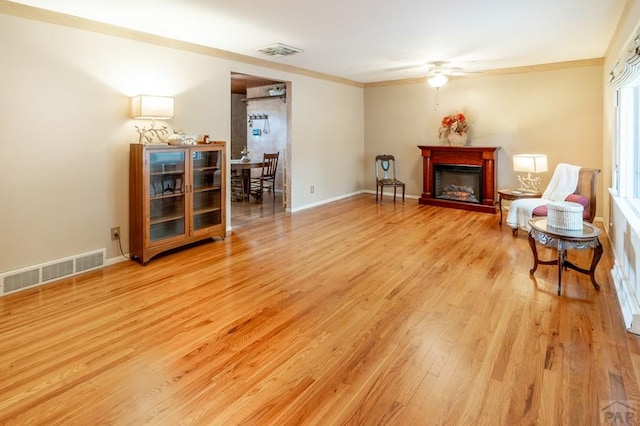 1329 Alexander Cir, Pueblo, CO 81001 - living area with ceiling fan, light wood finished floors, ornamental molding, and a fireplace