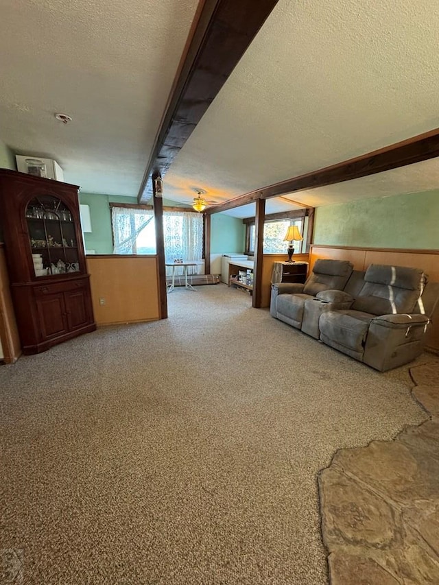 unfurnished living room with a wainscoted wall, carpet, and a textured ceiling