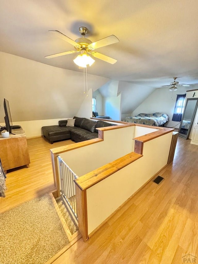 interior space with lofted ceiling, visible vents, ceiling fan, and light wood-style flooring