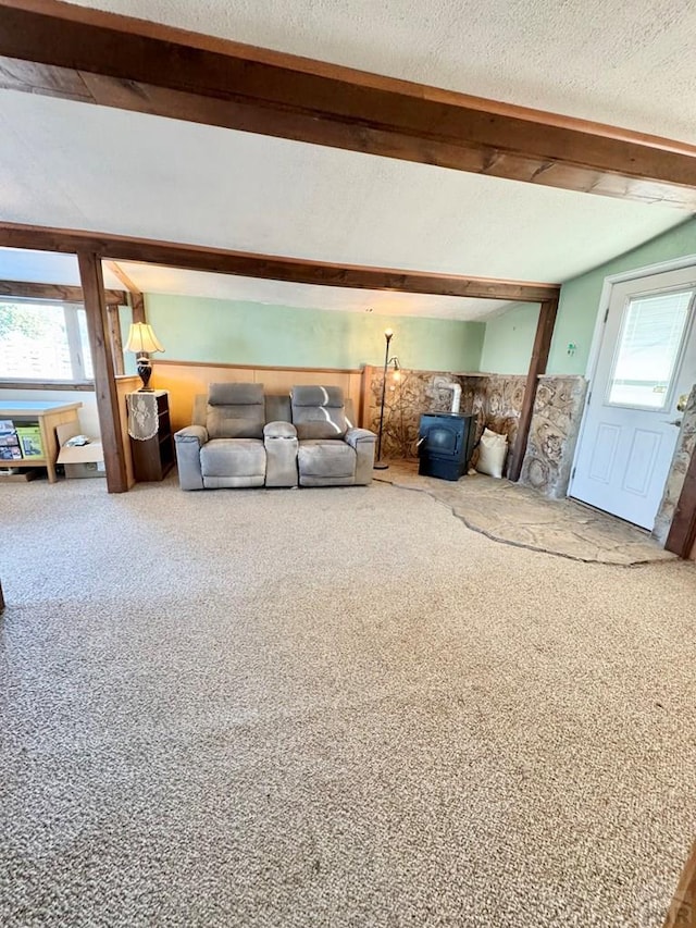 unfurnished living room with carpet, a textured ceiling, and beamed ceiling