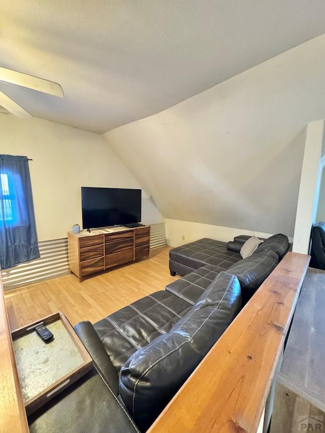 living area featuring vaulted ceiling, a textured ceiling, and wood finished floors