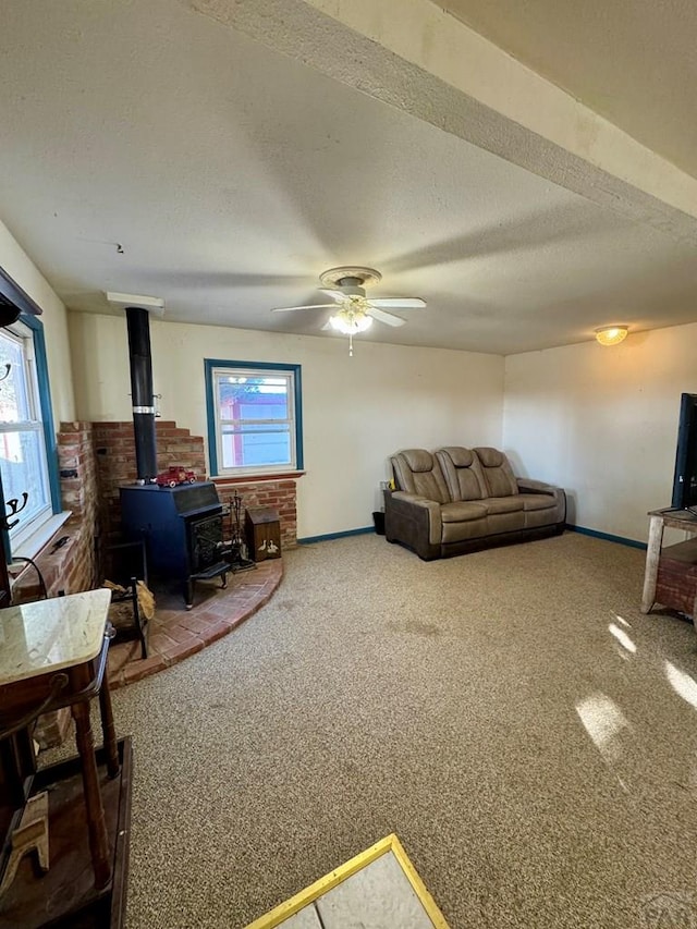 living room featuring a wood stove, carpet, plenty of natural light, and a textured ceiling