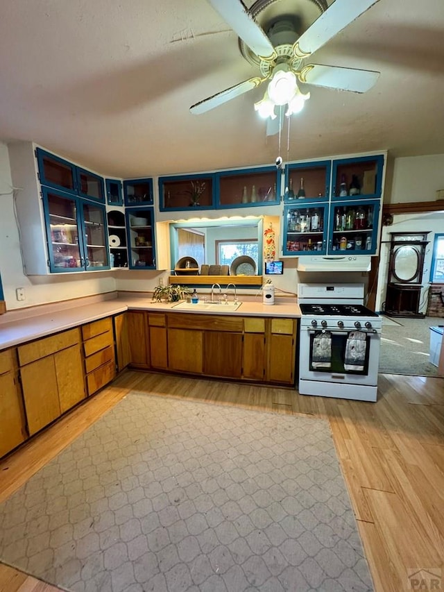 17345 US Highway 50, Las Animas, CO 81054 - kitchen with white range with gas stovetop, light wood-style flooring, light countertops, a ceiling fan, and glass insert cabinets