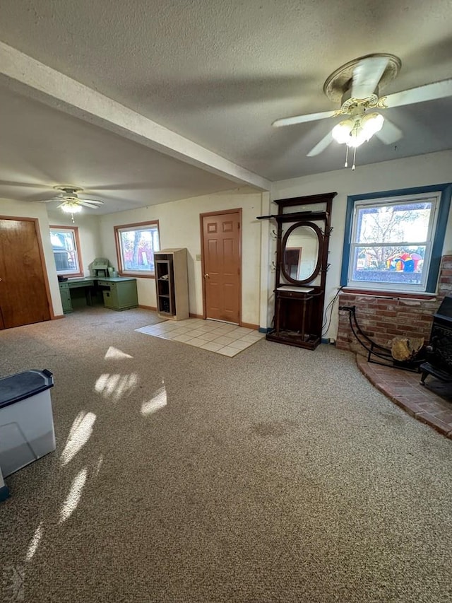 interior space featuring a textured ceiling, carpet flooring, a wood stove, and a ceiling fan