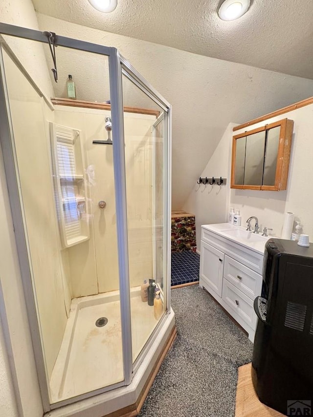 full bath featuring lofted ceiling, a stall shower, a textured ceiling, and vanity