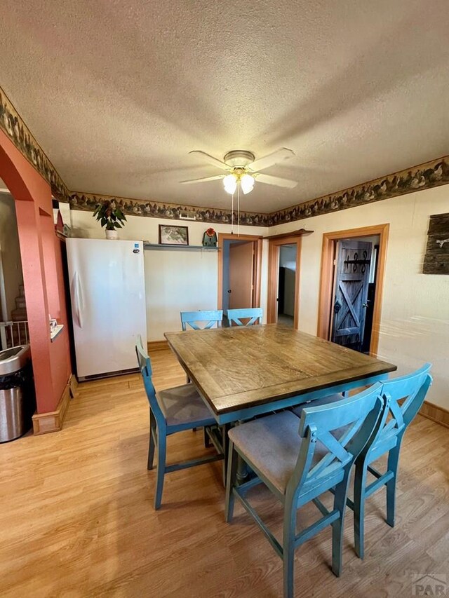 dining area with baseboards, ceiling fan, light wood-style flooring, and a textured ceiling