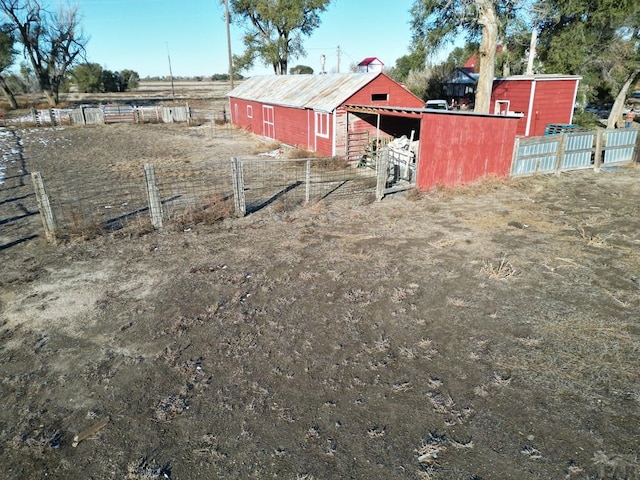 view of yard with a pole building, a rural view, an outdoor structure, and fence