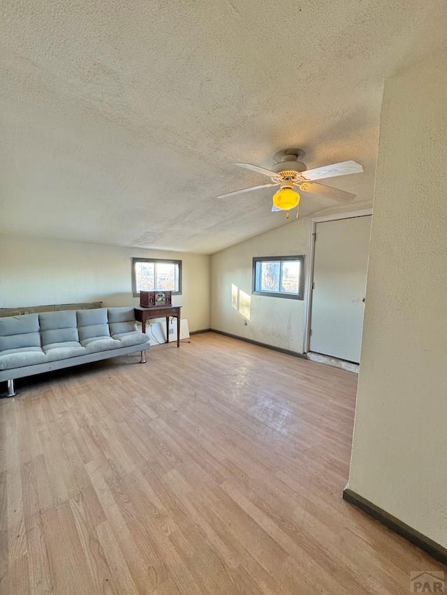 unfurnished living room with a textured ceiling, ceiling fan, plenty of natural light, and light wood-style flooring