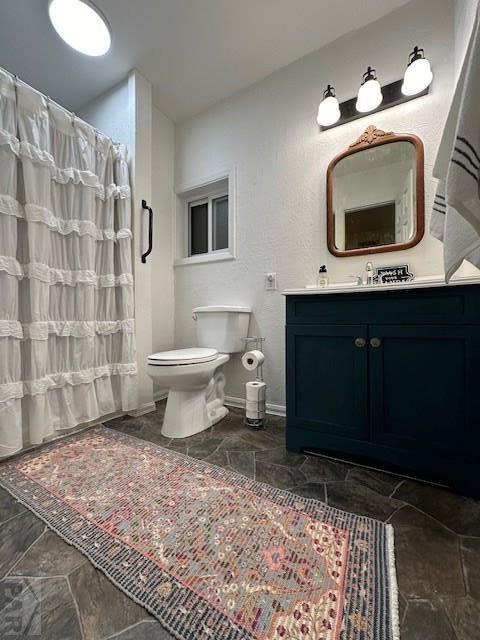 bathroom featuring baseboards, vanity, and toilet