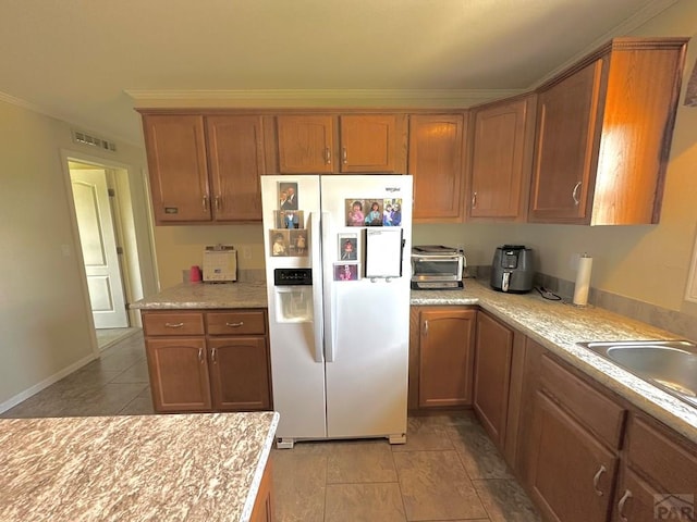 15406 County Rd E.25, Ordway, CO 81063 - kitchen featuring white refrigerator with ice dispenser, light countertops, light tile patterned flooring, ornamental molding, and brown cabinets