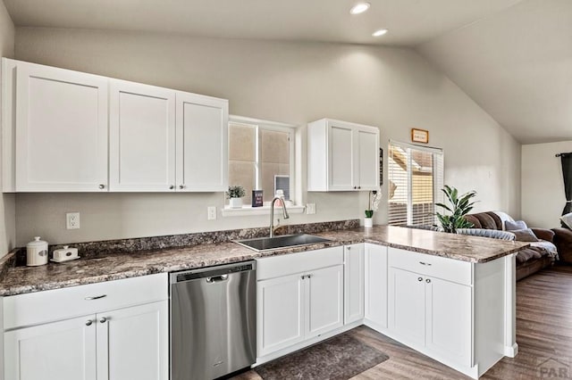 kitchen featuring white cabinets, lofted ceiling, open floor plan, stainless steel dishwasher, and a sink