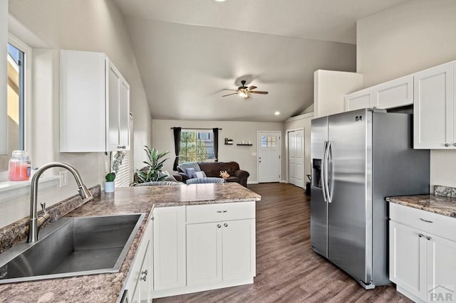 kitchen featuring open floor plan, stainless steel fridge, a sink, and white cabinetry