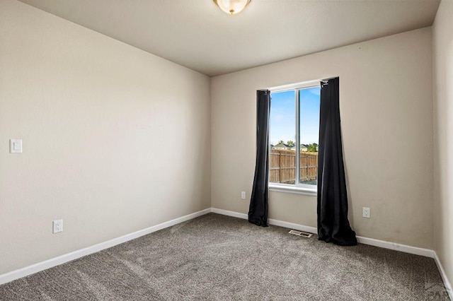 empty room with carpet flooring, visible vents, and baseboards