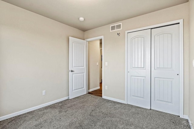 unfurnished bedroom featuring carpet, a closet, visible vents, and baseboards