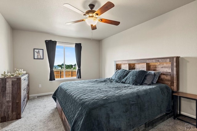 bedroom featuring light carpet, a ceiling fan, and baseboards