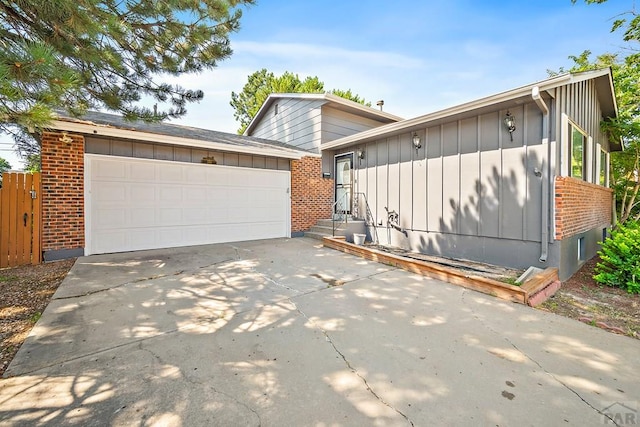 130 Montcalm Dr, Pueblo, CO 81005 - view of front of property with board and batten siding, brick siding, an attached garage, concrete driveway, and entry steps
