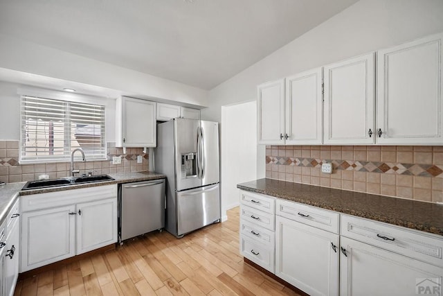 130 Montcalm Dr, Pueblo, CO 81005 - kitchen featuring appliances with stainless steel finishes, decorative backsplash, white cabinets, light wood finished floors, and lofted ceiling